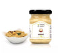 "Ein Glas Hummus neben einer Schale mit serviertem Hummus, dekoriert mit Kichererbsen und Kräutern.\t"